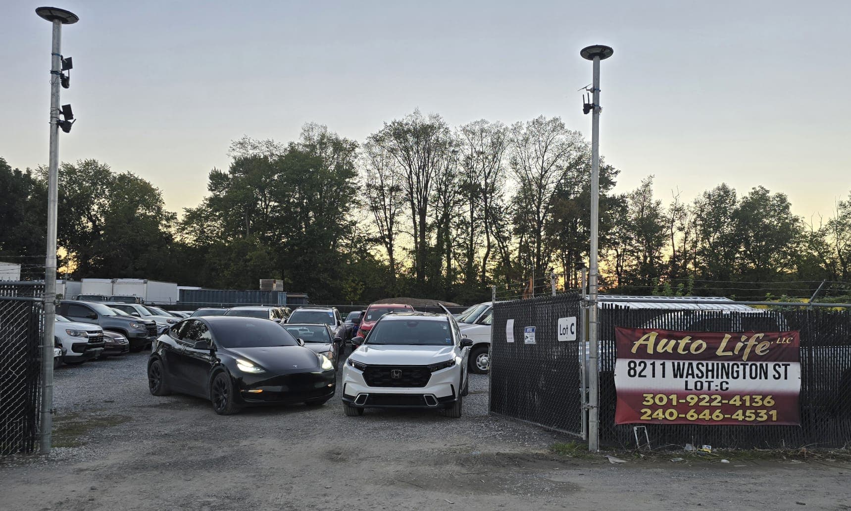 Entrance to the AUTO LIFE lot at Lot C: cars parked behind the gate and the Auto Life LLC sign on the fence.